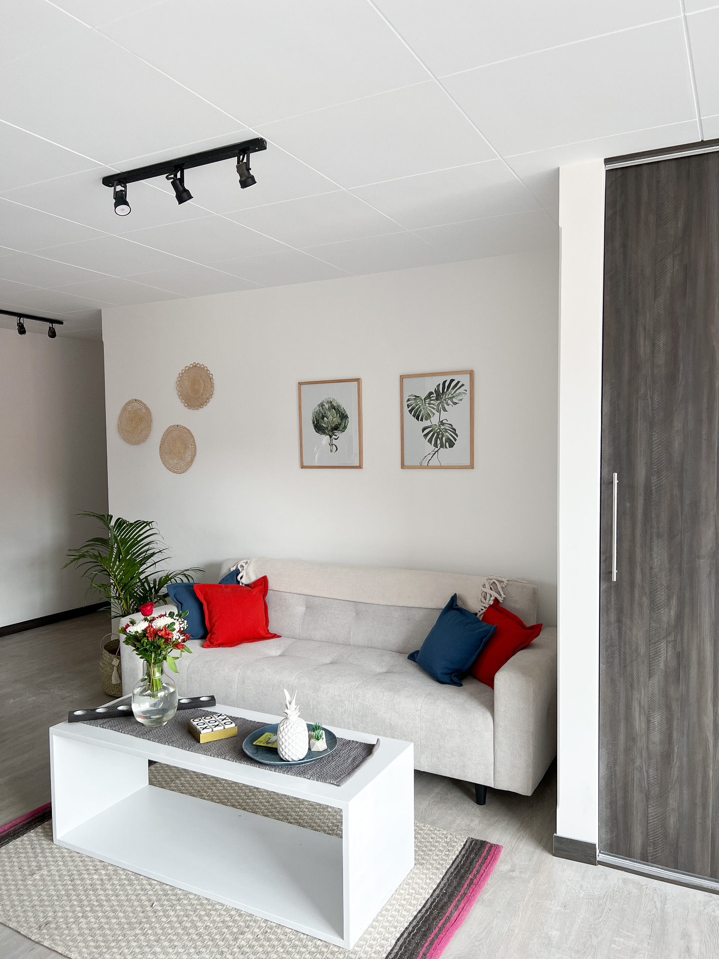 Bright living room at Calm Illimani 1 with a soft sofa, woven wall baskets, plants, and colorful cushions